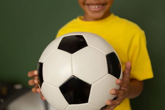 Ein Kind hält einen Fußball in der Hand.