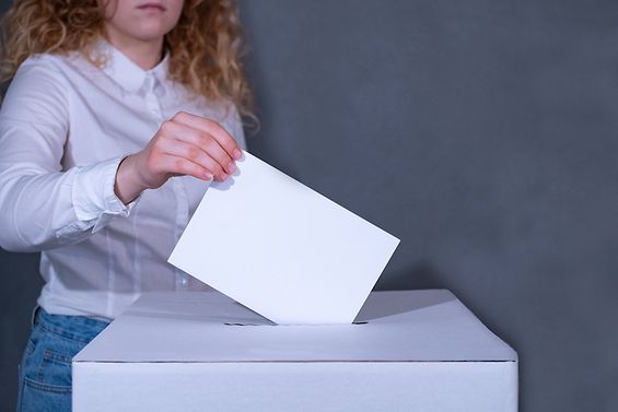 Eine Person gibt einen Stimmzettel an einer Wahlurne ab.