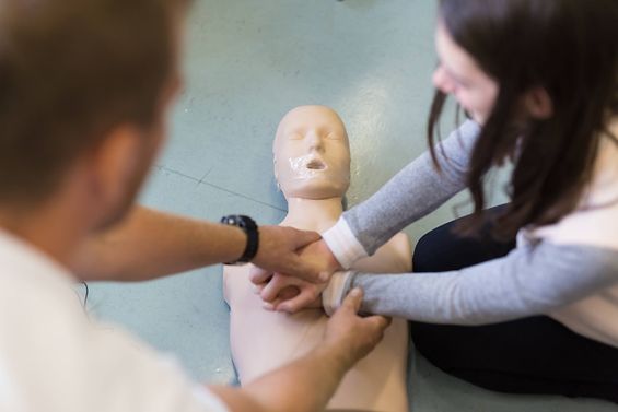 Eine Schülerin übt eine Herzdruckmassage an einer Puppe.