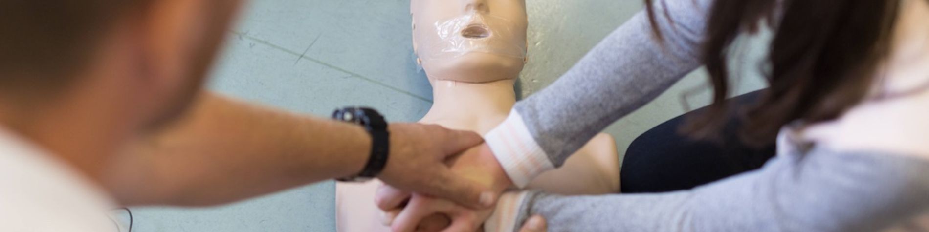 Eine Schülerin übt eine Herzdruckmassage an einer Puppe.