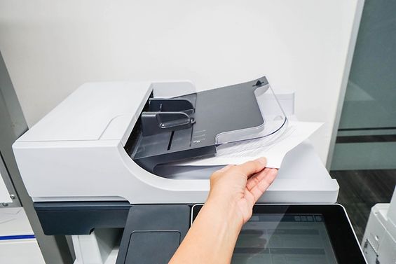 Eine Hand nimmt ein Dokument aus einem Drucker.
