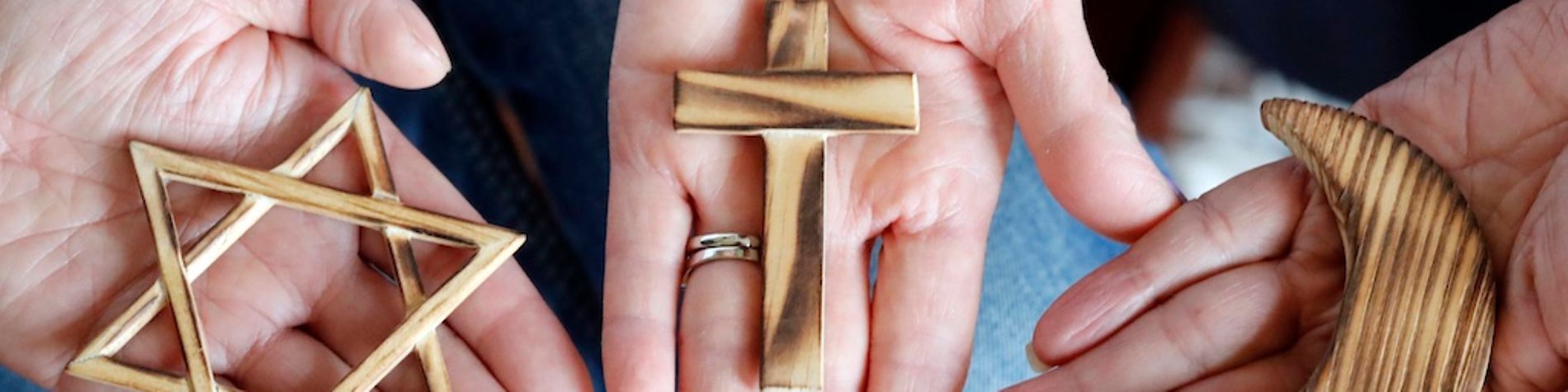 Drei Hände halten jeweils ein religiöses Symbol.