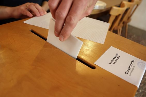 Ein Zettel wird in eine Wahlurne gesteckt.