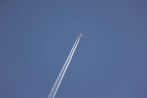 Ein Flugzeug hinterlässt Kondensstreifen am Himmel.