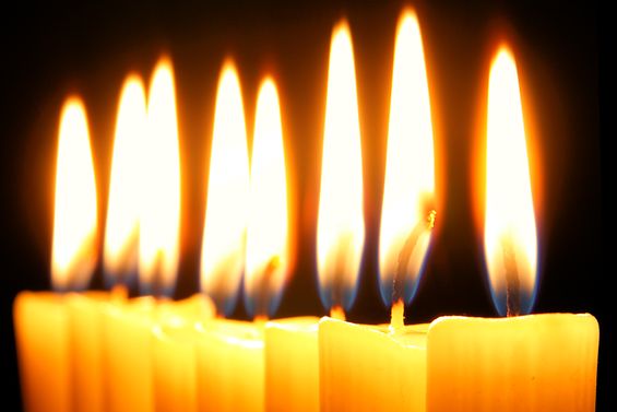 Acht brennende Kerzen auf schwarzem Hintergrund