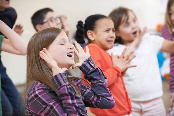 Kinder stellen verschiedene Emotionen im Theaterunterricht dar.