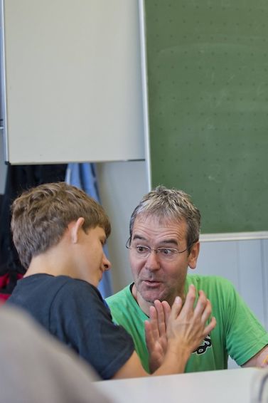 Ein Lehrer betreut ein Kind, während eine Lehrerin unterrichtet.