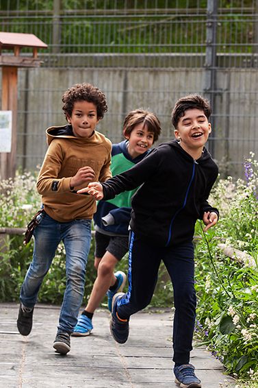 Kinder rennen durch den Naturschulhofgarten.